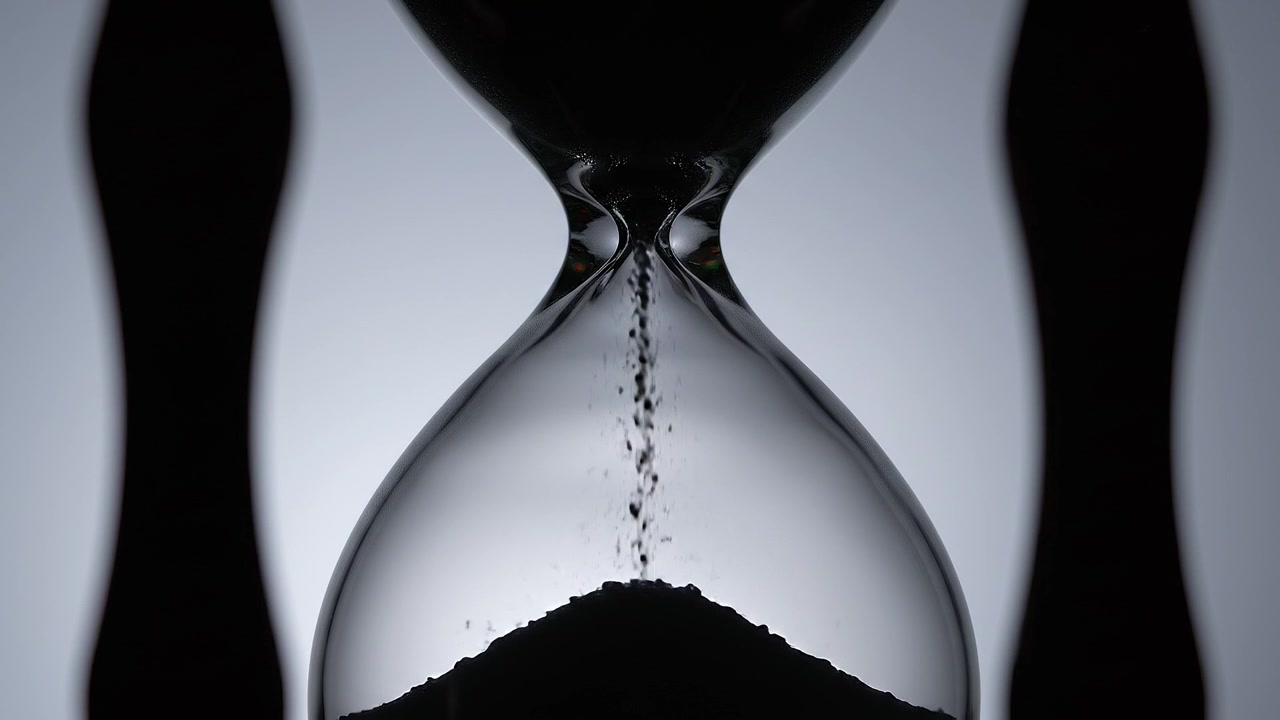 Black and White Close-up of Sand Flowing Through Hourglass