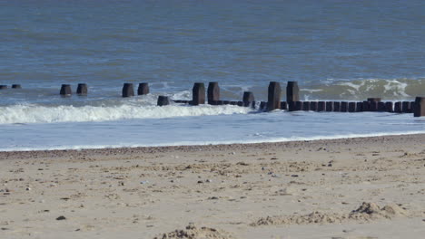 shot of the waves crashing over the sea defence groynes at walcott beach