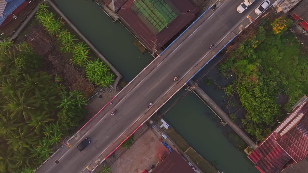 Ripresa aerea del traffico che attraversa un ponte sul fiume all'alba, Thailandia