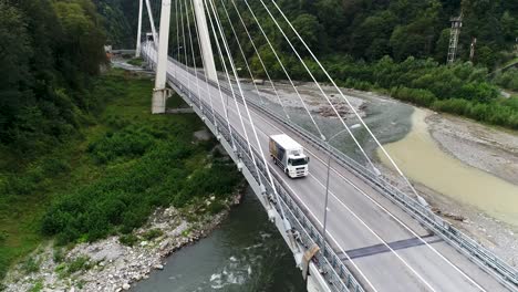 truck on a cable-stayed bridge over a river in mountains