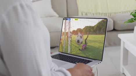 video de una persona sentada en el sofá y viendo un partido de fútbol en una computadora portátil