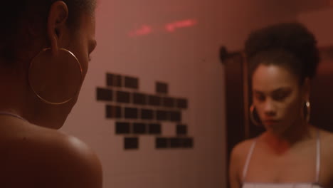 hermosa chica poniéndose lápiz labial mientras mira el espejo en un baño de bar