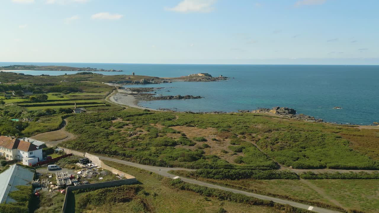 vuelo de aviones no tripulados sobre los páramos y la costa hacia fort doyle, costa norte de guernsey, con vistas al mar en un día soleado y tranquilo.