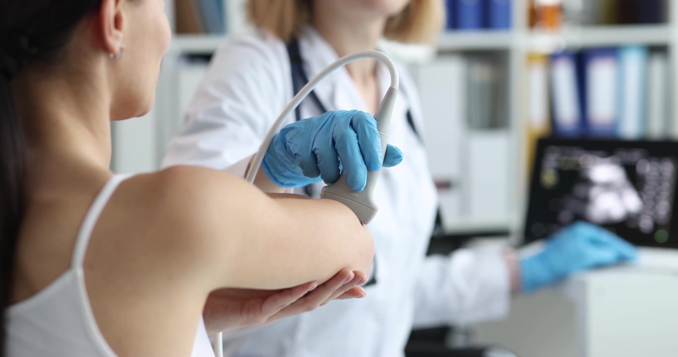 Profesional médico realiza ecografía en el codo de una mujer
