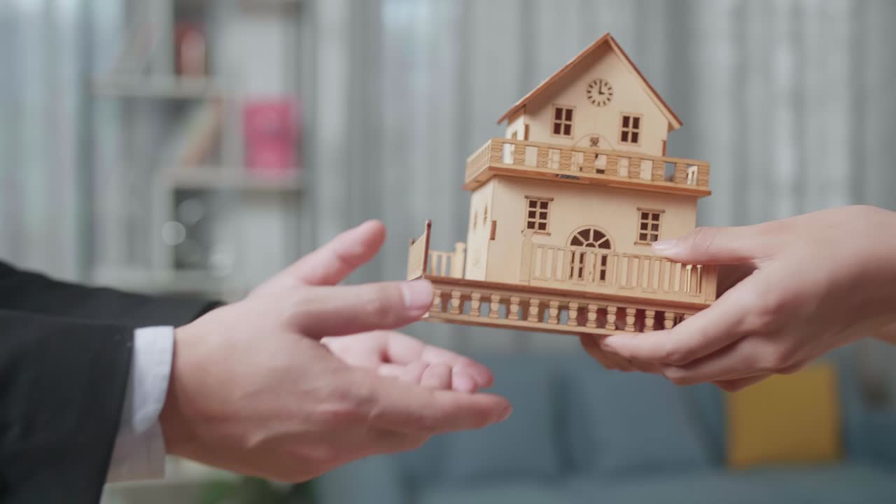 cerca de la mano del agente de bienes raíces dando el modelo de la casa a una mujer en la casa para la venta