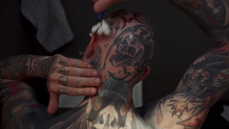 Shirtless Tattooed Inmate Shaving Head in front of Sink in Prison Cell