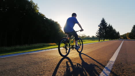 silhouette teenager goes on a flat road against the setting sun