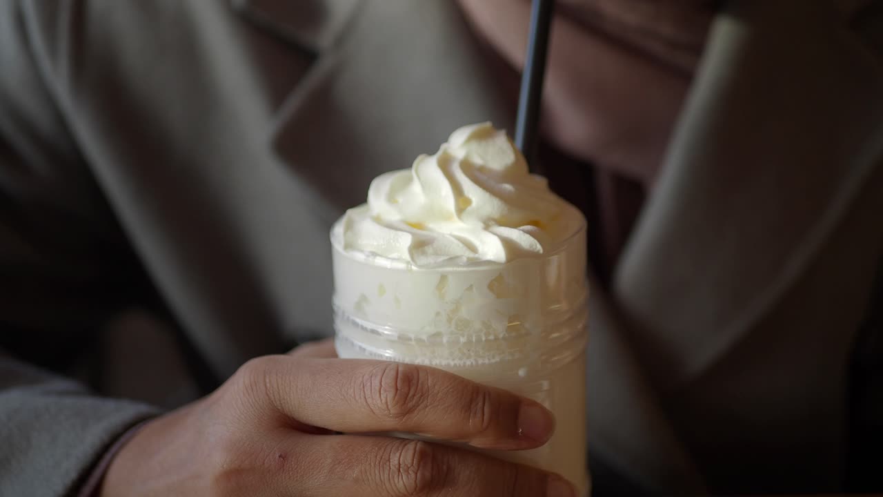 Person som holder en kopp kaffe med pisket krem