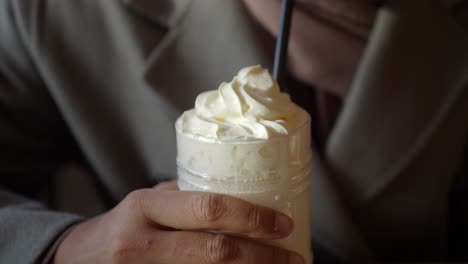 person holding a cup of coffee with whipped cream