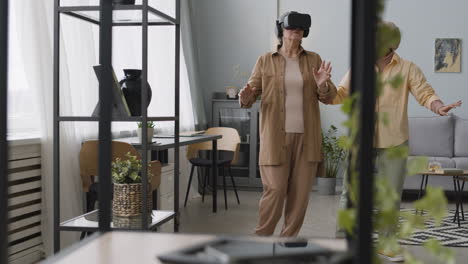 mujer árabe de mediana edad ayudando a una anciana a usar gafas de realidad virtual en casa 1