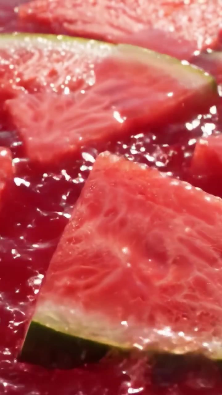 Primo piano vivace di fette di anguria fresca che galleggiano in liquido succoso, mettendo in mostra la polpa succosa e la buccia verde in una scena rinfrescante ed estiva.