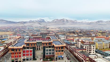 sertar city skyline, buildings in daytime, mountains in background, china tibet landscape, aerial drone view