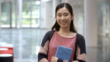 Female-Asian-university-student-walking-into-focus-in-lobby