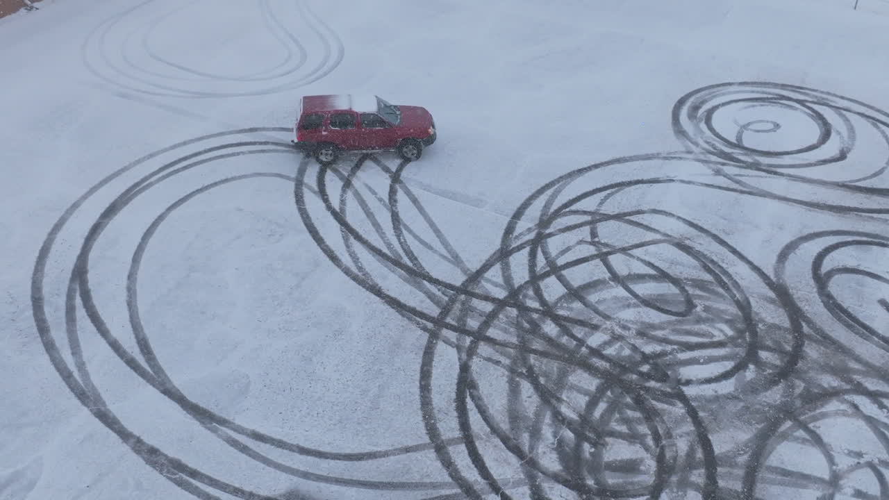 Birds eye view slow motion footage of a truck doing donuts in a snow covered parking lot in Chattanooga, TN.