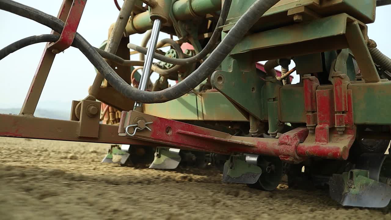 Close up of farming seeding drill machine at work pulled by tractor, close up of agricultural modern mechanical equipment