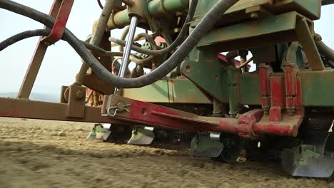 close up of farming seeding drill machine at work pulled by tractor, close up of agricultural modern mechanical equipment