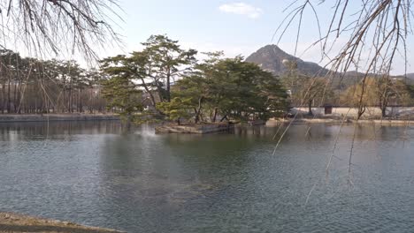 pond with artificial island at gyeongbokgung palace in seoul, south korea. mountain in distant background. wide shot