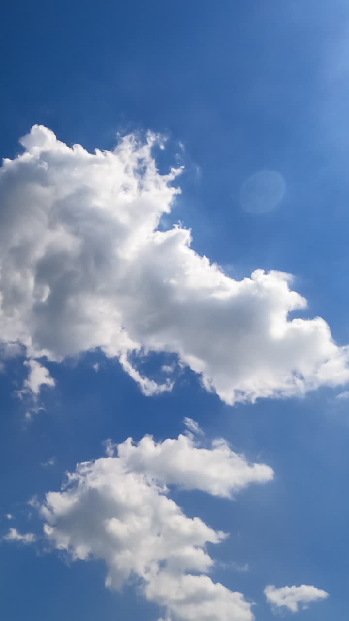 Beautiful soft light clouds transforming in the bright rays of summer sun. Low angle view timelapse. Vertical video