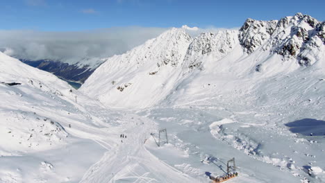 Aerial-birds-eye-shot-over-ski-region-with-many-skier-skiing-downhill-snowy-slope-in-winter-season-Kauntertal,-Austria