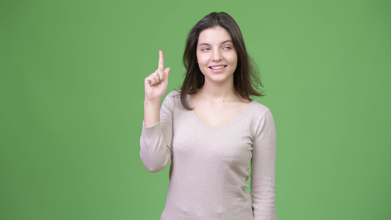 Young happy beautiful woman thinking while pointing finger up