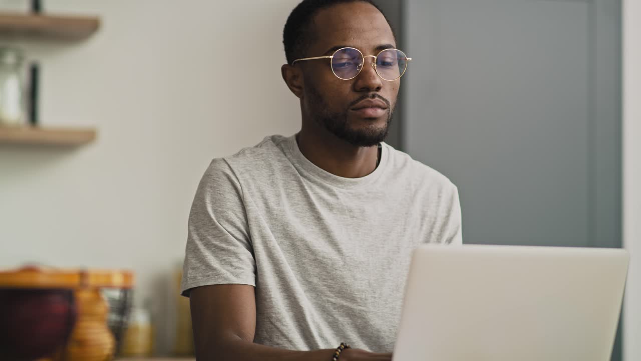 Tilt up video of black man using laptop at home