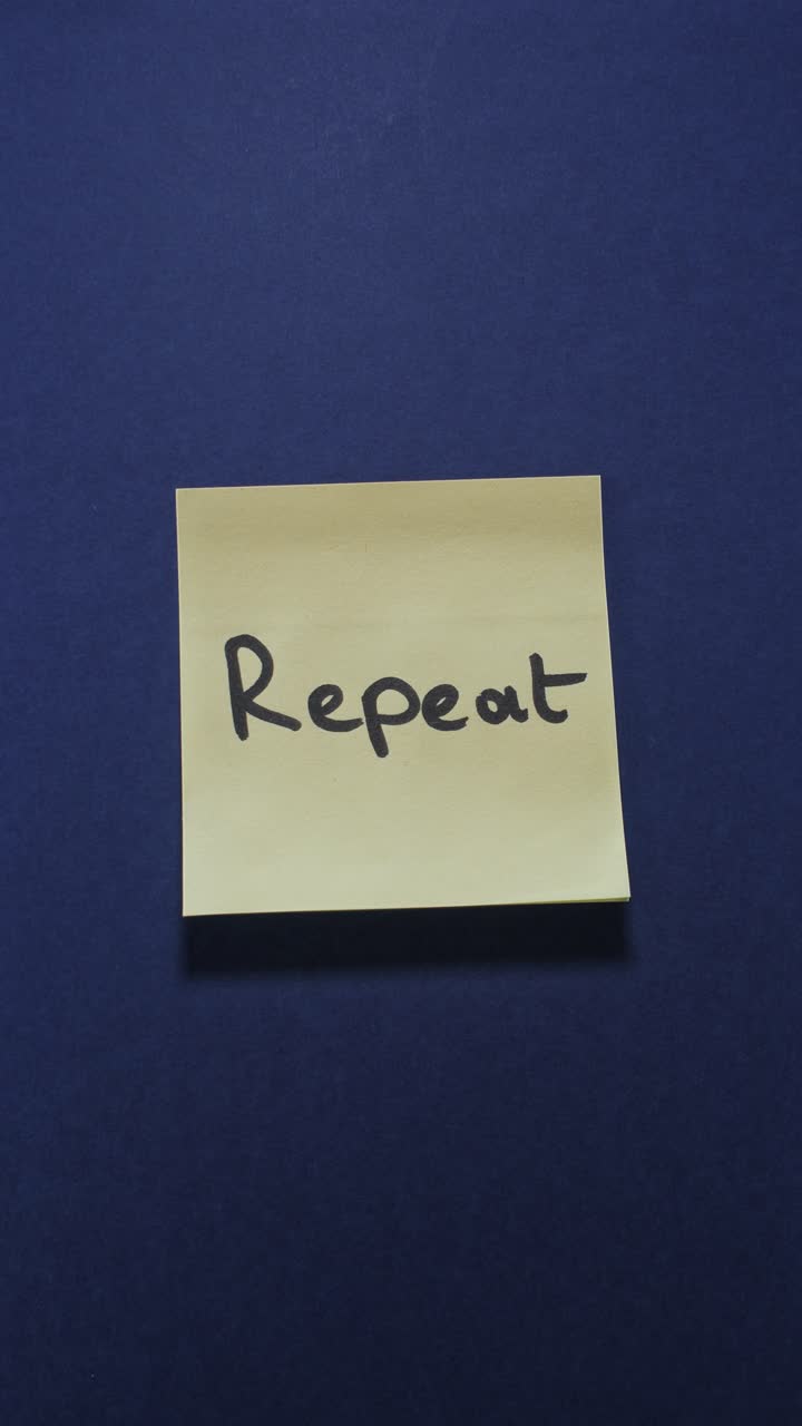 Posting Repeat sticky note on dark blue wall, emphasizing consistency and routine