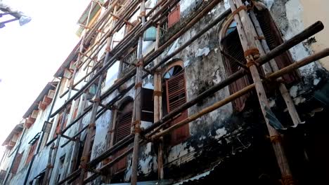 tilting shot of a rundown building in zanzibar undergoing repairs with wooden scaffolding