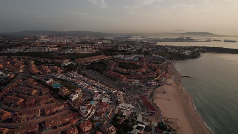 slow-motion aerial sideways video on algeciras city in spain with landscape view of city and commercial harbor during sunrise