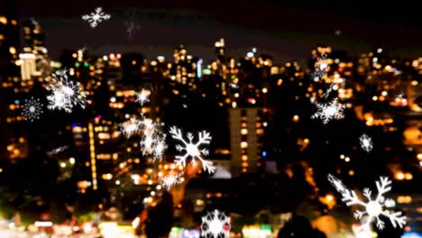 multiple snowflakes icons falling against aerial view of night cityscape