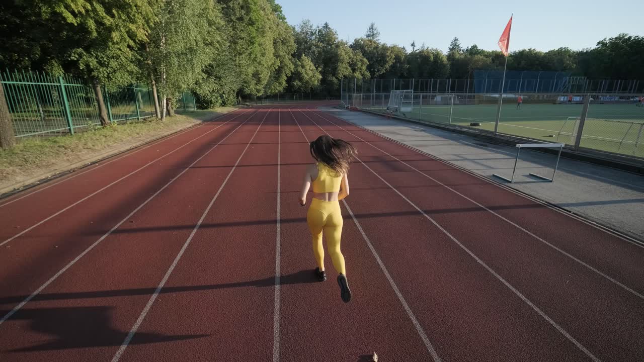 mujer corriendo en una pista al aire libre con ropa deportiva amarilla