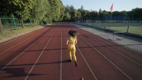 woman running on outdoor track in yellow sportswear