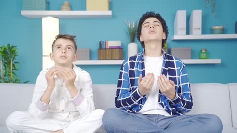 Two-praying-brothers-looking-at-each-other-at-home-and-smiling.