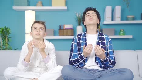 two praying brothers looking at each other at home and smiling.