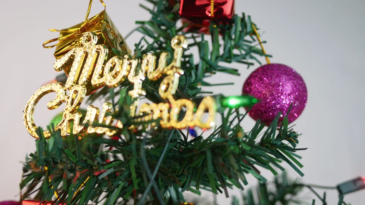 색 배경에 고립 된 새해 2020 년을 위해 baubles, 조명 및 작은 선물 선물로 장식 된 크리스마스 트리.