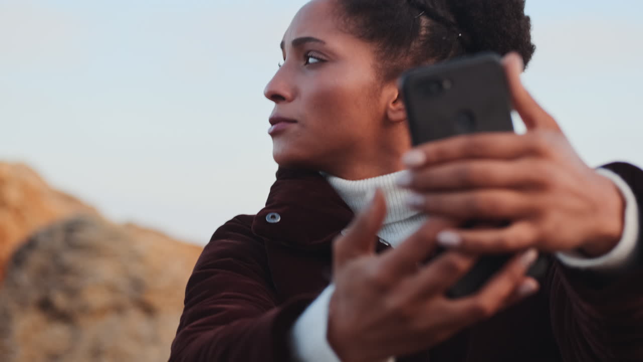 una chica afroamericana haciendo una llamada de video al aire libre.