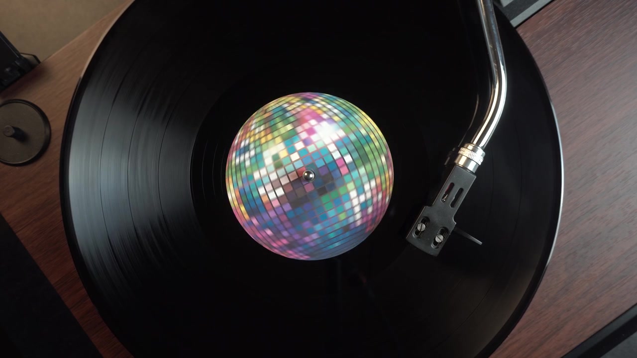 Disco in vinile con adesivo a forma di palla da discoteca che suona su un giradischi, vista dall'alto