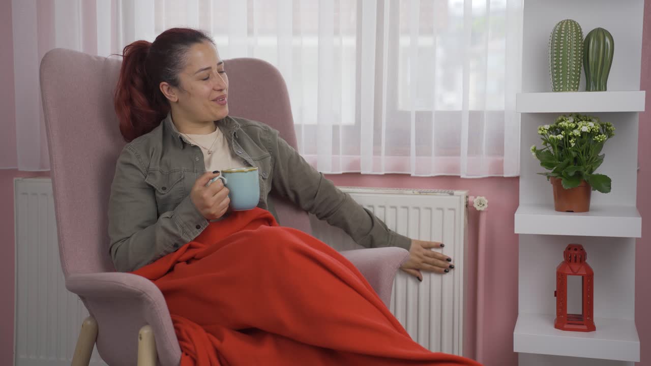 창문 앞에서 뜨거운 음료를 마시는 여자는  ⁇ 집을 만집니다.