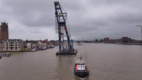 tug boat, determined and sturdy, guides floating platform carrying the crane