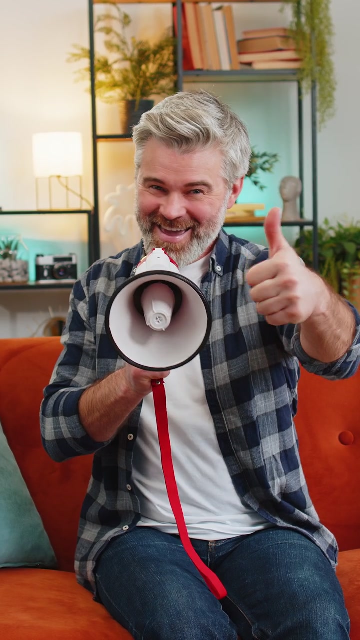 Uomo anziano felice che parla al megafono proclamando notizie annunciando ad alta voce pubblicità a casa