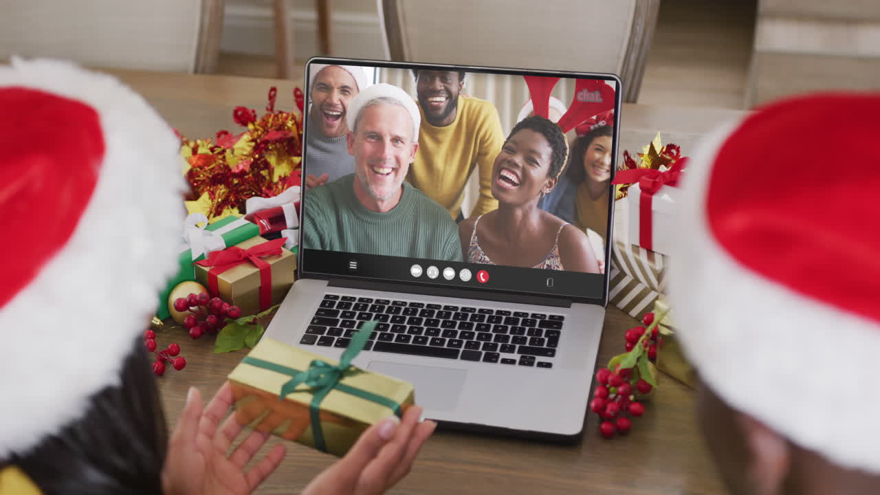pareja diversa con sombreros de santa teniendo llamada de video portátil con amigos diversos felices