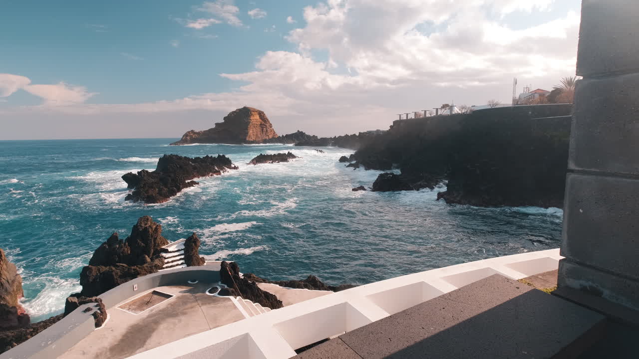 toma pov caminando hacia las olas rompiendo en la costa del soleado porto moniz, madeira