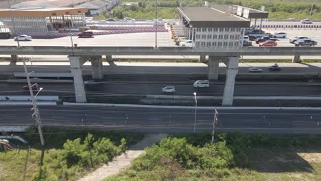 Tiro-De-Seguimiento-A-Lo-Largo-De-La-Pasarela-De-Peaje-En-La-Autopista,-Los-Vehículos-Que-Conducen-Por-Debajo-De-La-Carretera