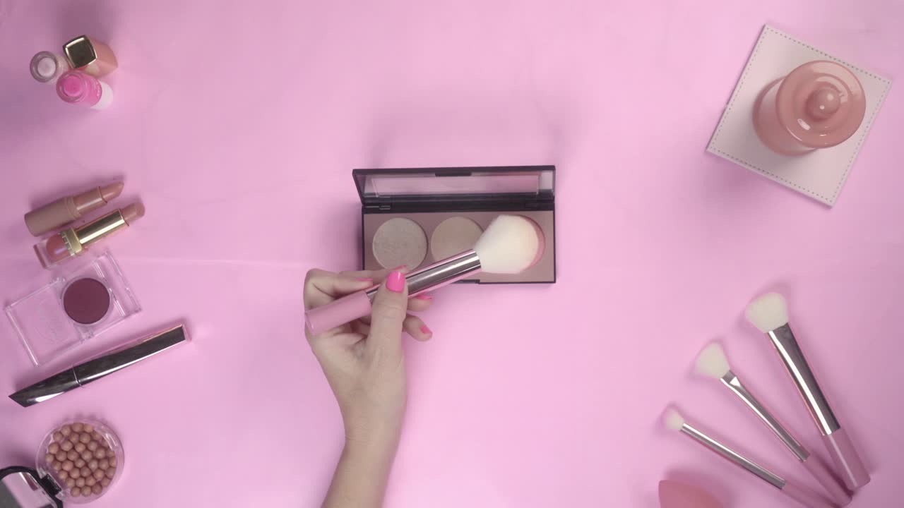 Woman's Hands Preparing Makeup Palette and Brushes on Pink Background