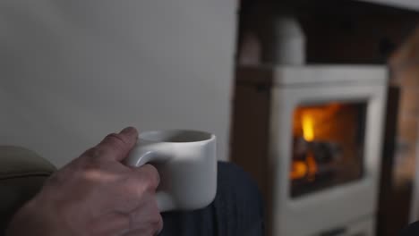 Kaffee-In-Der-Hand-Vor-Dem-Holzofen