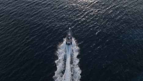 drone following shot of powerful yacht speeding over blue sea during sunlight