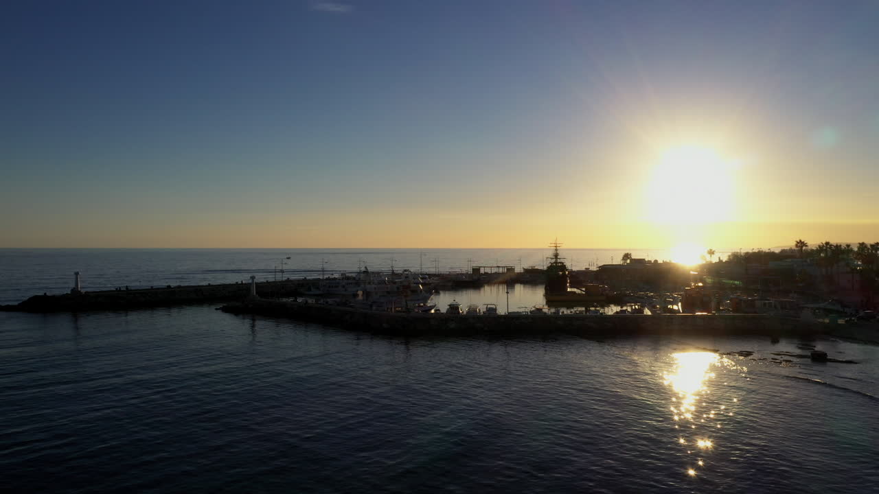 Flygfoto över en liten fiskehamn under den gyllene timmen.