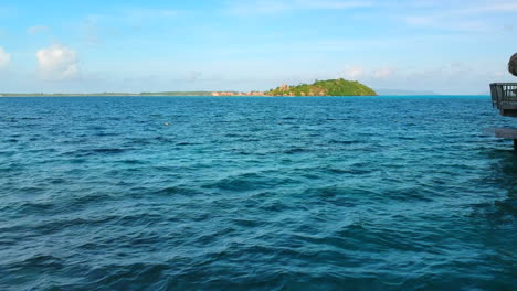 Carro-Sobre-El-Agua-Hacia-Una-Isla-Con-Bungalow-Sobre-El-Agua-En-El-Océano-Pacífico,-Bora-Bora,-Polinesia-Francesa