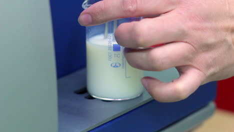 biologist put measuring cup with a liquid in laboratory equipment. closeup