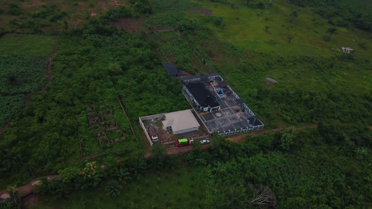 Aerial shot of a lone compound surrounded by greenery in Ibadan, Nigeria. Drone moves in for a top-down view. A single house built in minst of greenery in Africa.