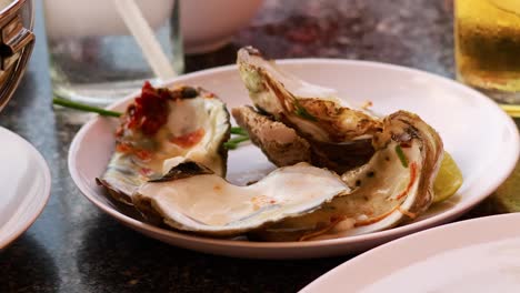 hands savoring oysters with lime and sauce